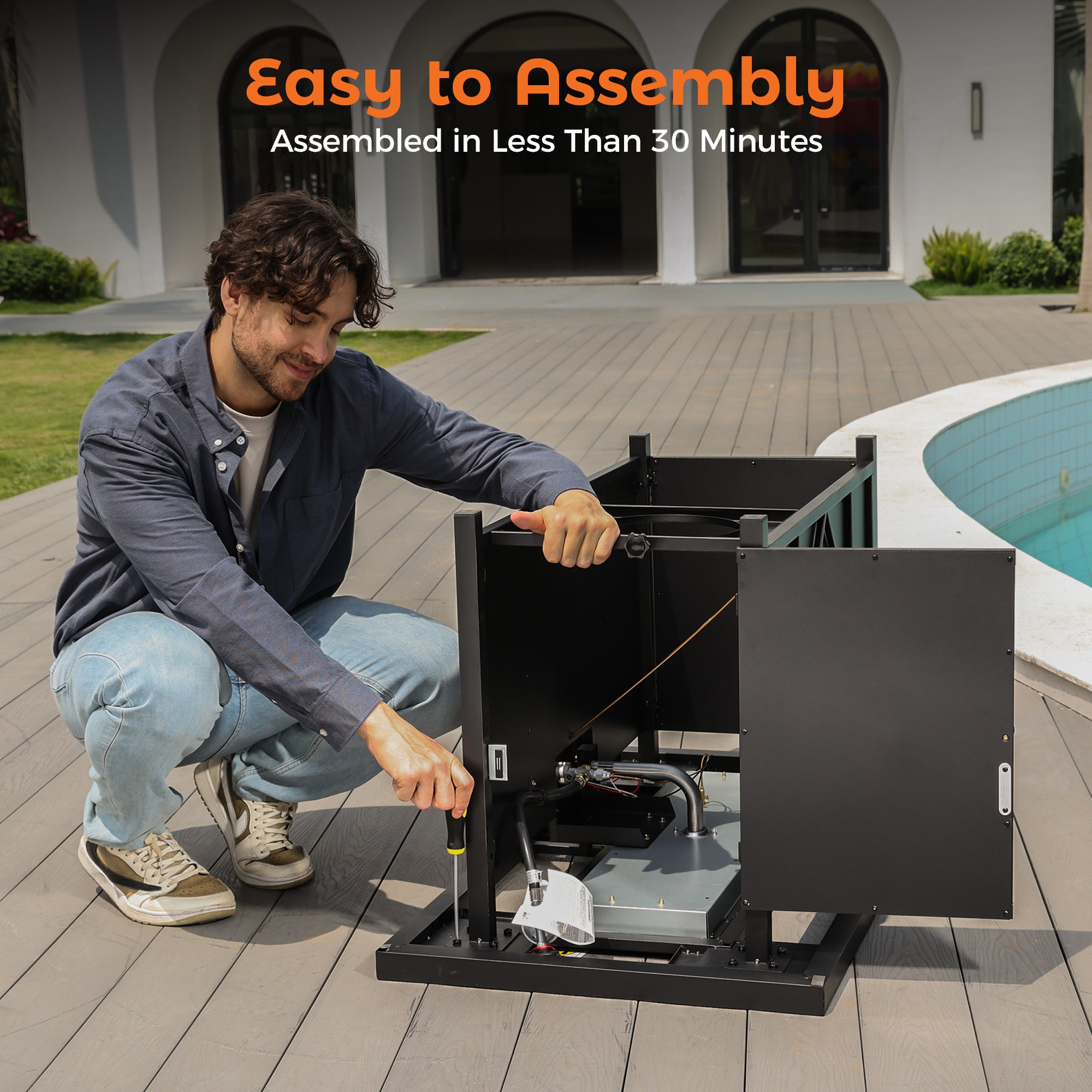Man assembling black 42-inch propane fire pit table with screwdriver on wooden deck, showing easy assembly process.