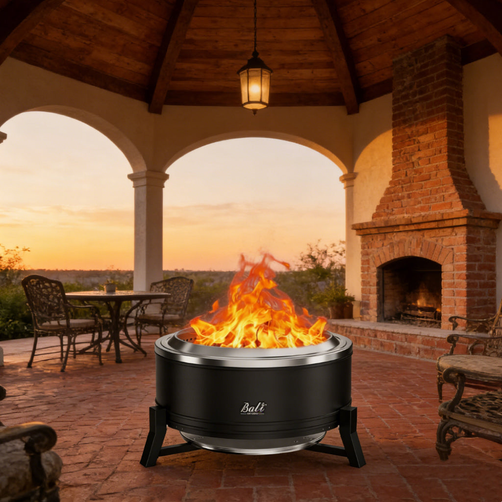 Black 27-inch smokeless outdoor fire pit with a stainless steel rim, burning brightly on a brick patio at sunset.
