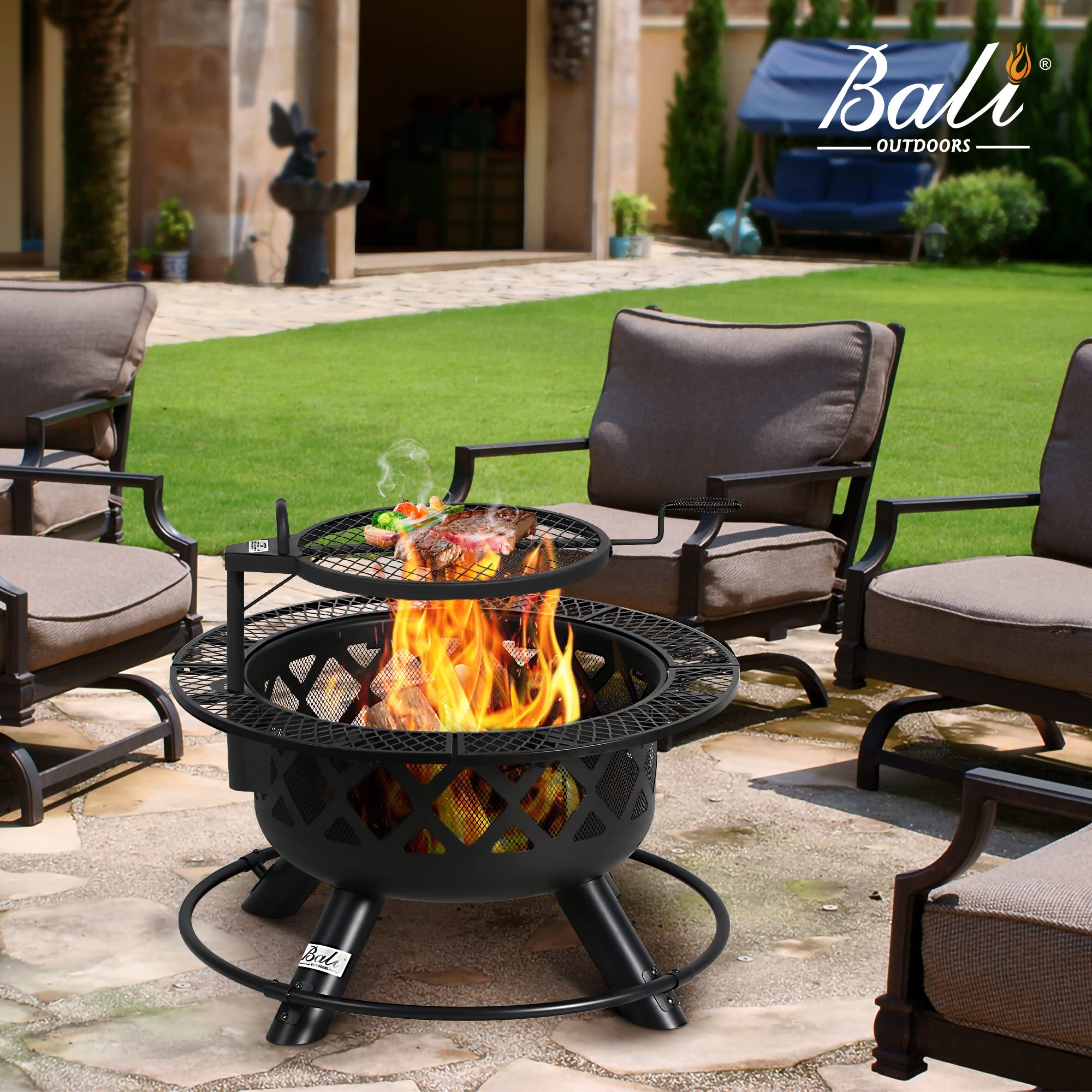 32 inch black outdoor wood fire pit with rotatable grill cooking steak and vegetables on patio with chairs.