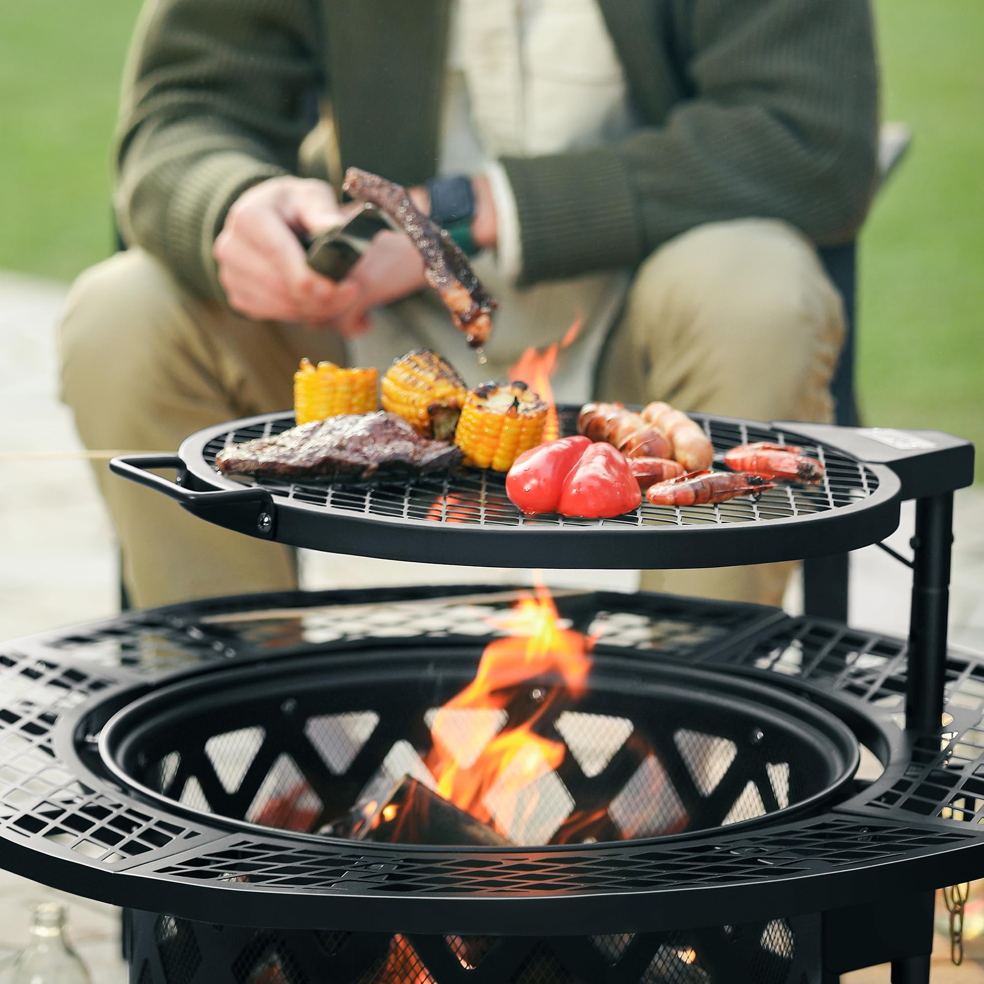 Black 32 inch wood fire pit grilling steak, corn, sausages, and peppers over a fire.