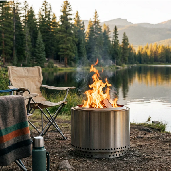 A compact portable fire pit set up on a patio with chairs around it at dusk