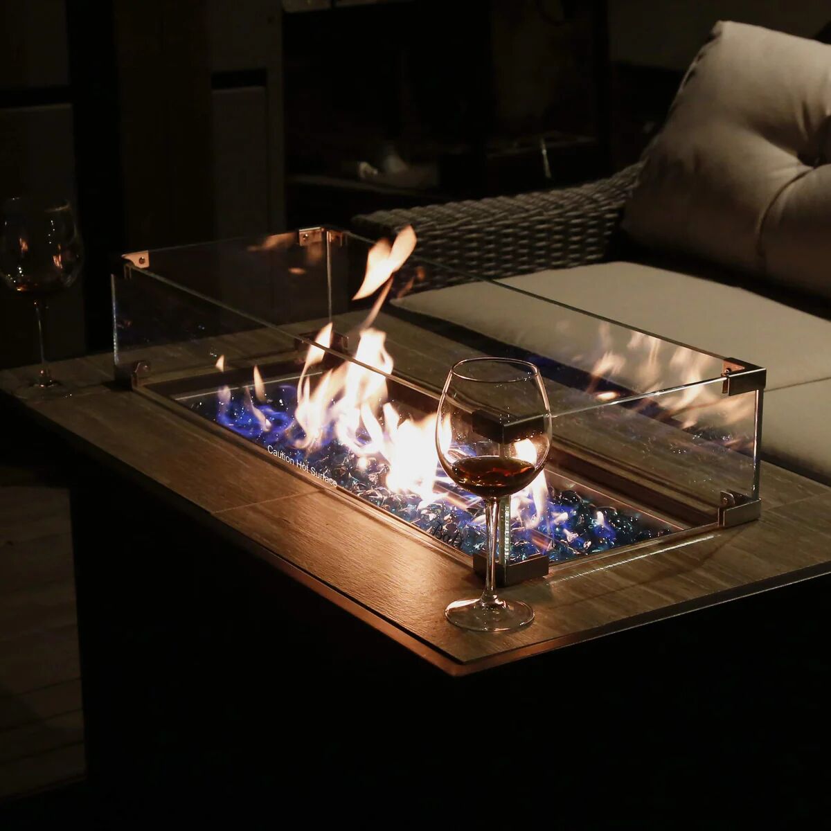 Close-up of a gas fire pit table with a glass of red wine.